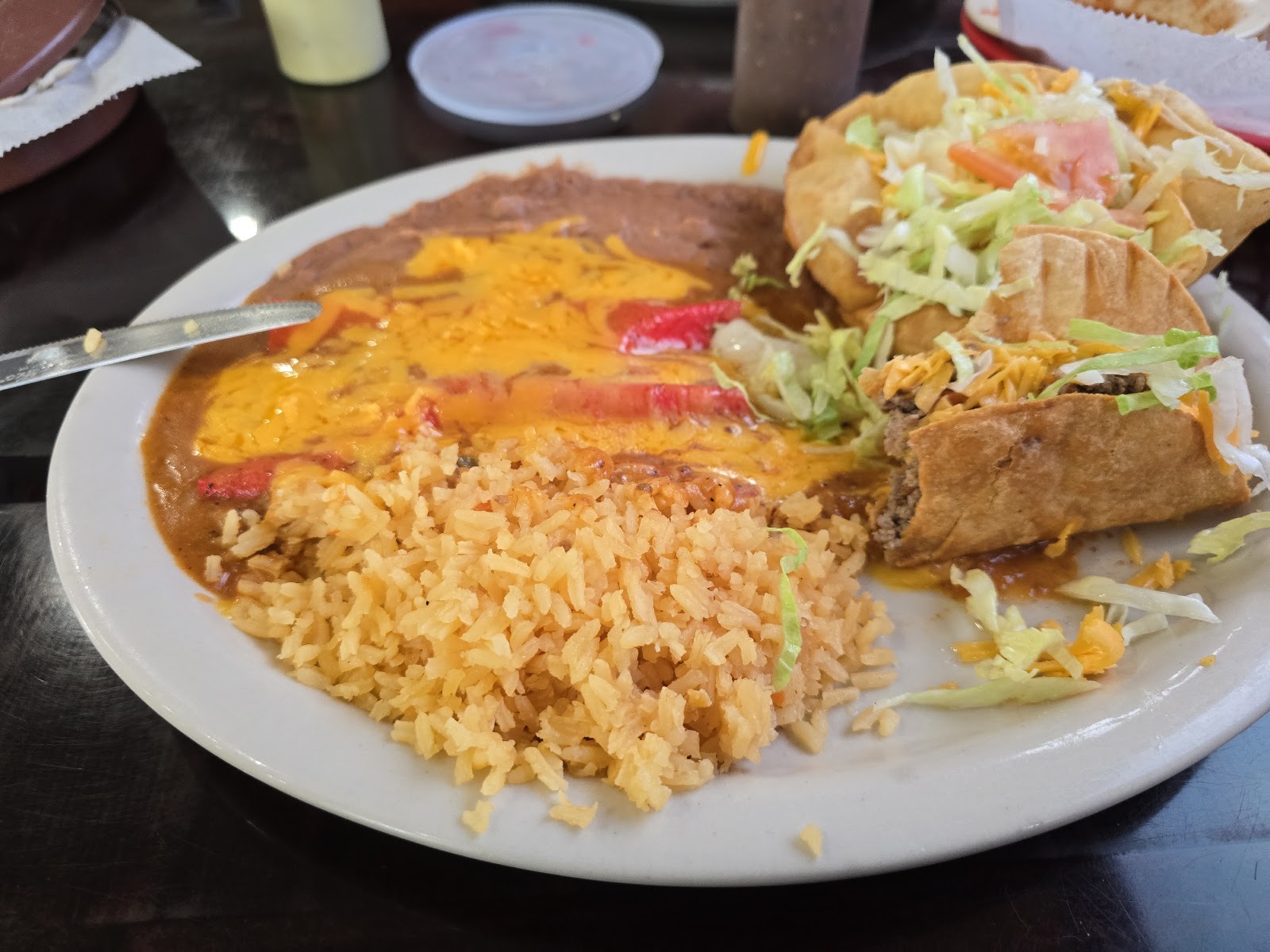Combination plate with puffy tacos, rice, beans, and cheese enchilada